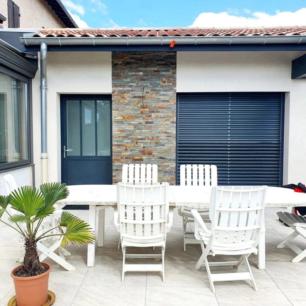 Façade de la maison avec porte vitrée en aluminium et volet à lames orientables