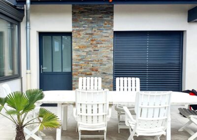 Façade de la maison avec porte vitrée en aluminium et volet à lames orientables